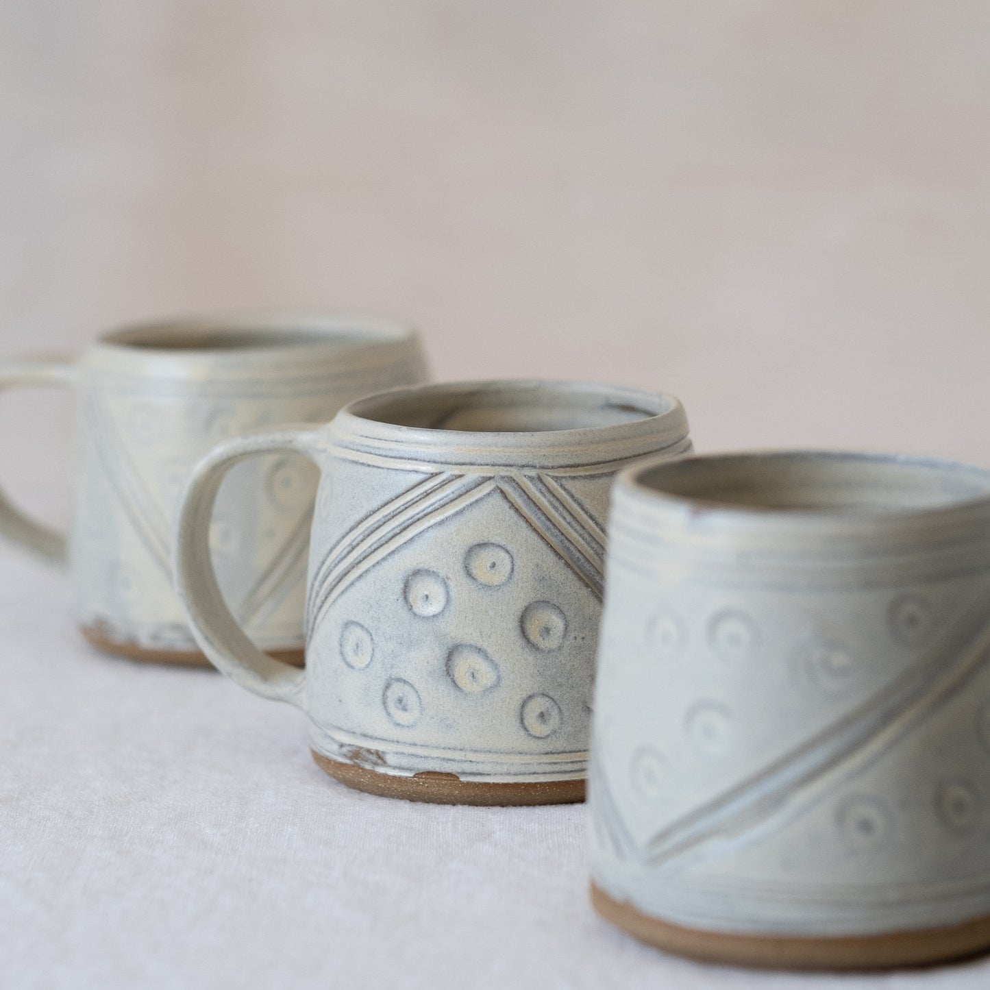 Trio of yellow hand carved pottery mugs with handles